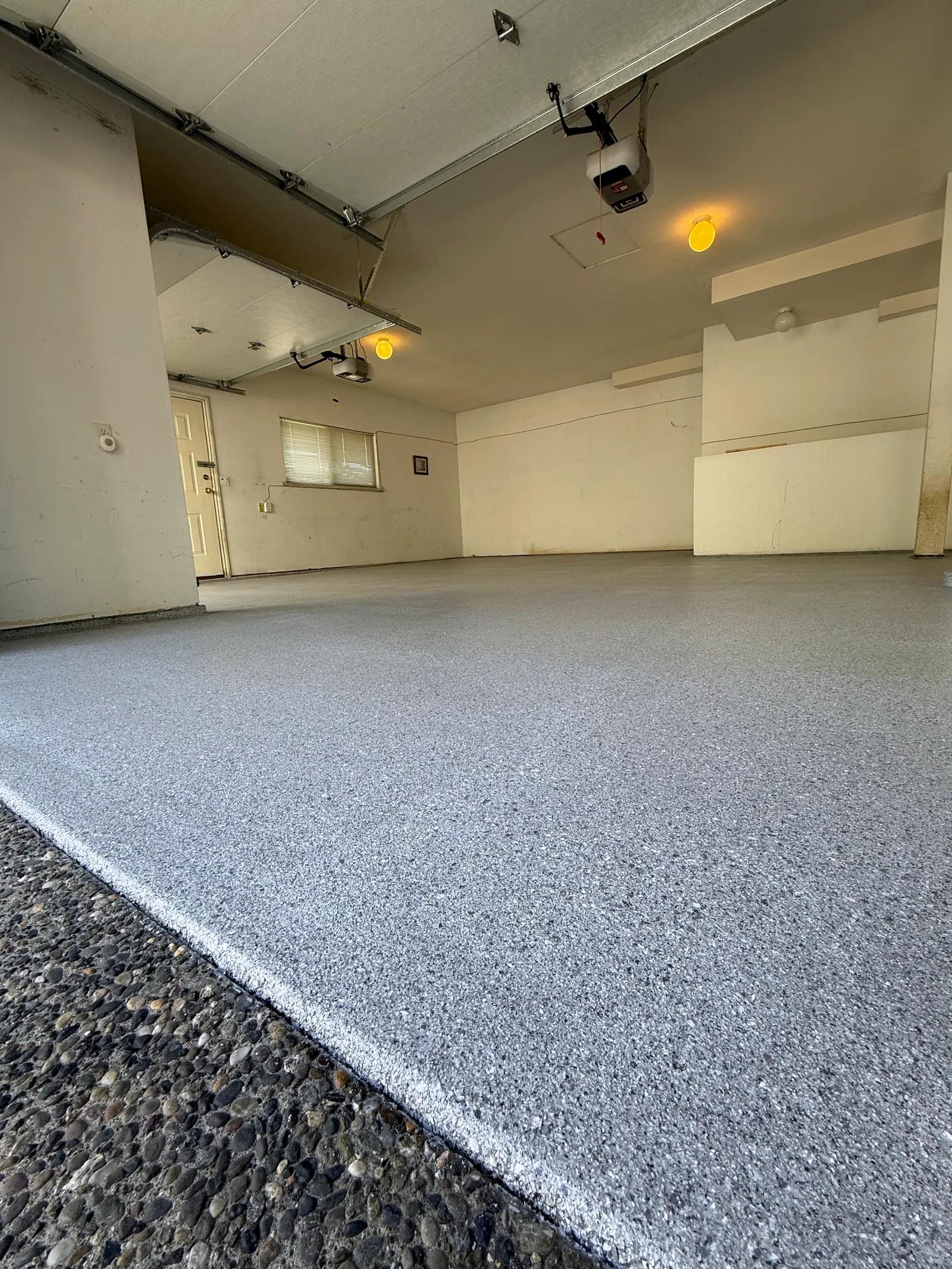Older attached garage with a fresh light grey flake floor finished neatly at the door threshold