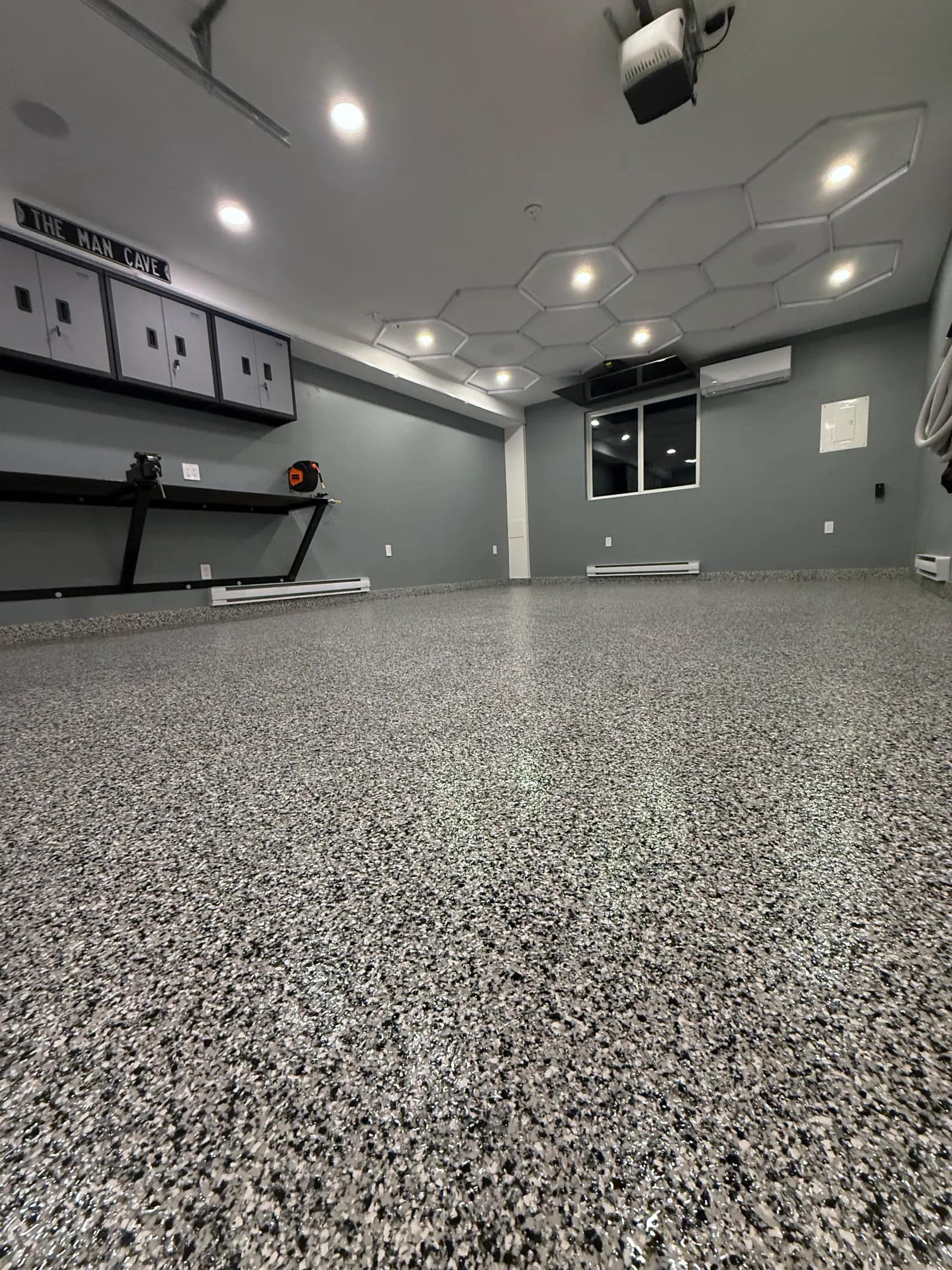 Home garage set up as a hangout, with a grey and black flake epoxy floor under hexagon ceiling lights